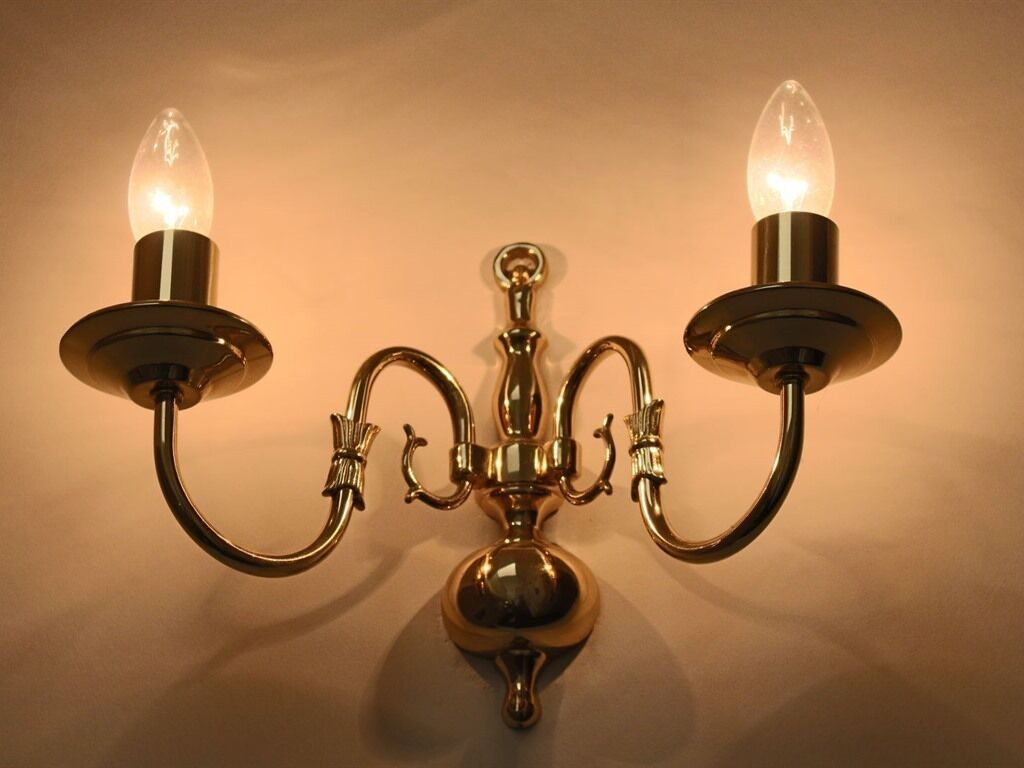 Een wandlamp met drie armen en twee lichtbollen.