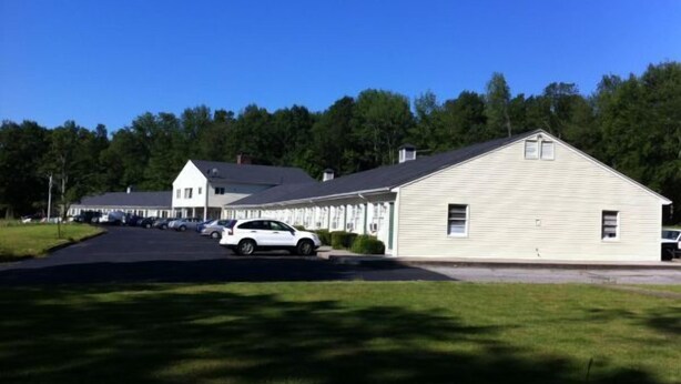 A two-story building with a large garage and a covered parking area. - Ashford Motel (Ashford)