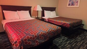 Two double beds with patterned bedspreads, a nightstand with a lamp, and a framed picture on the wall. - Ashford Motel (Ashford)