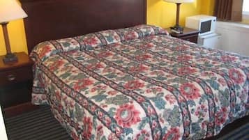 Una cama bien hecha con una colcha de estampado floral, dos lámparas de noche y una mesita de noche con lámpara.