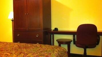 Una habitación de hotel con cama, escritorio, silla y armario.