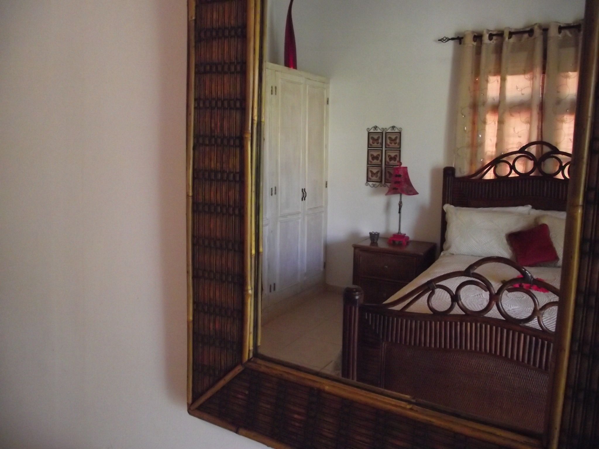 A bedroom with a wooden bed, a nightstand, a mirror, and a door.