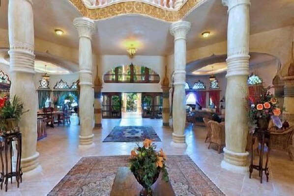 A spacious lobby with high ceilings, large columns, and a central floral arrangement.