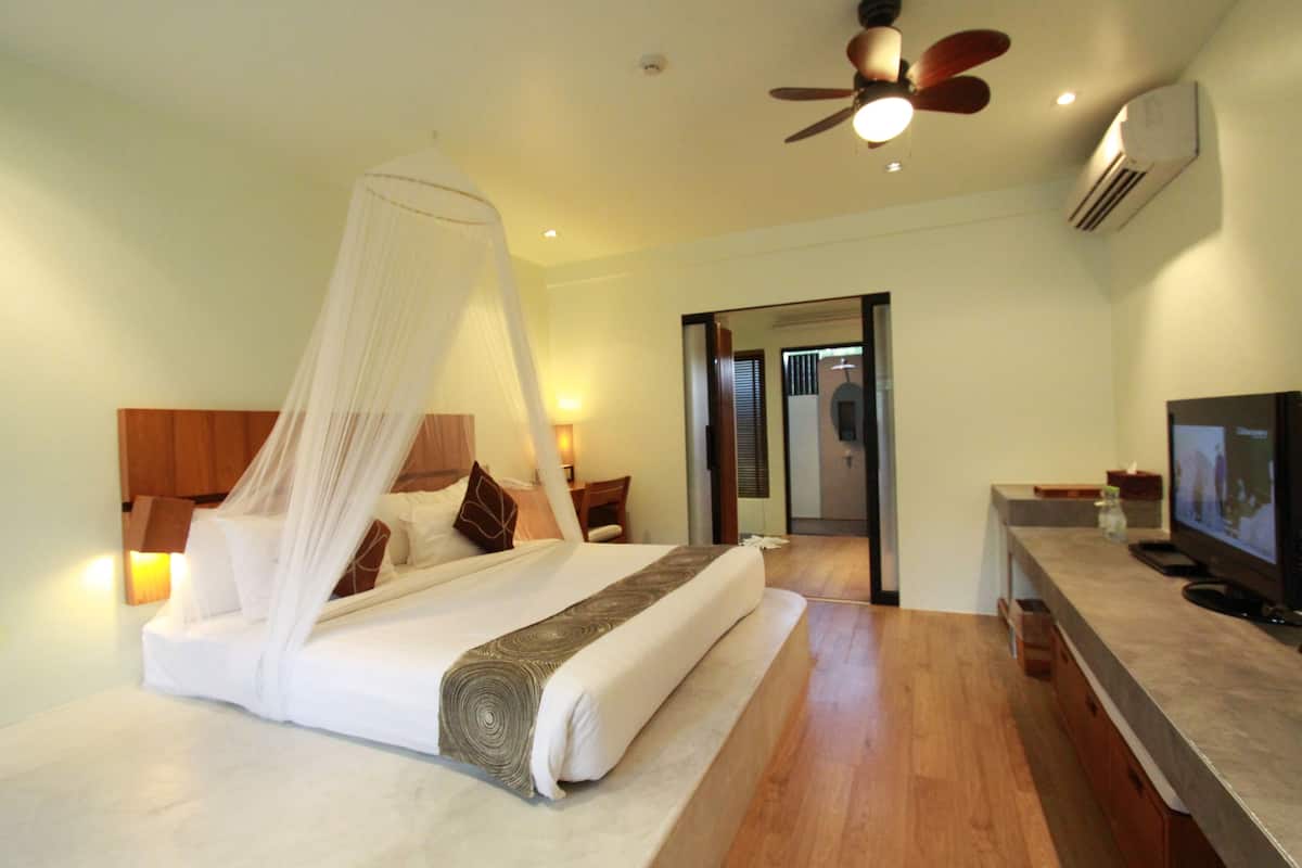 Une chambre à coucher avec un lit, une table de chevet, une télévision et un ventilateur de plafond.