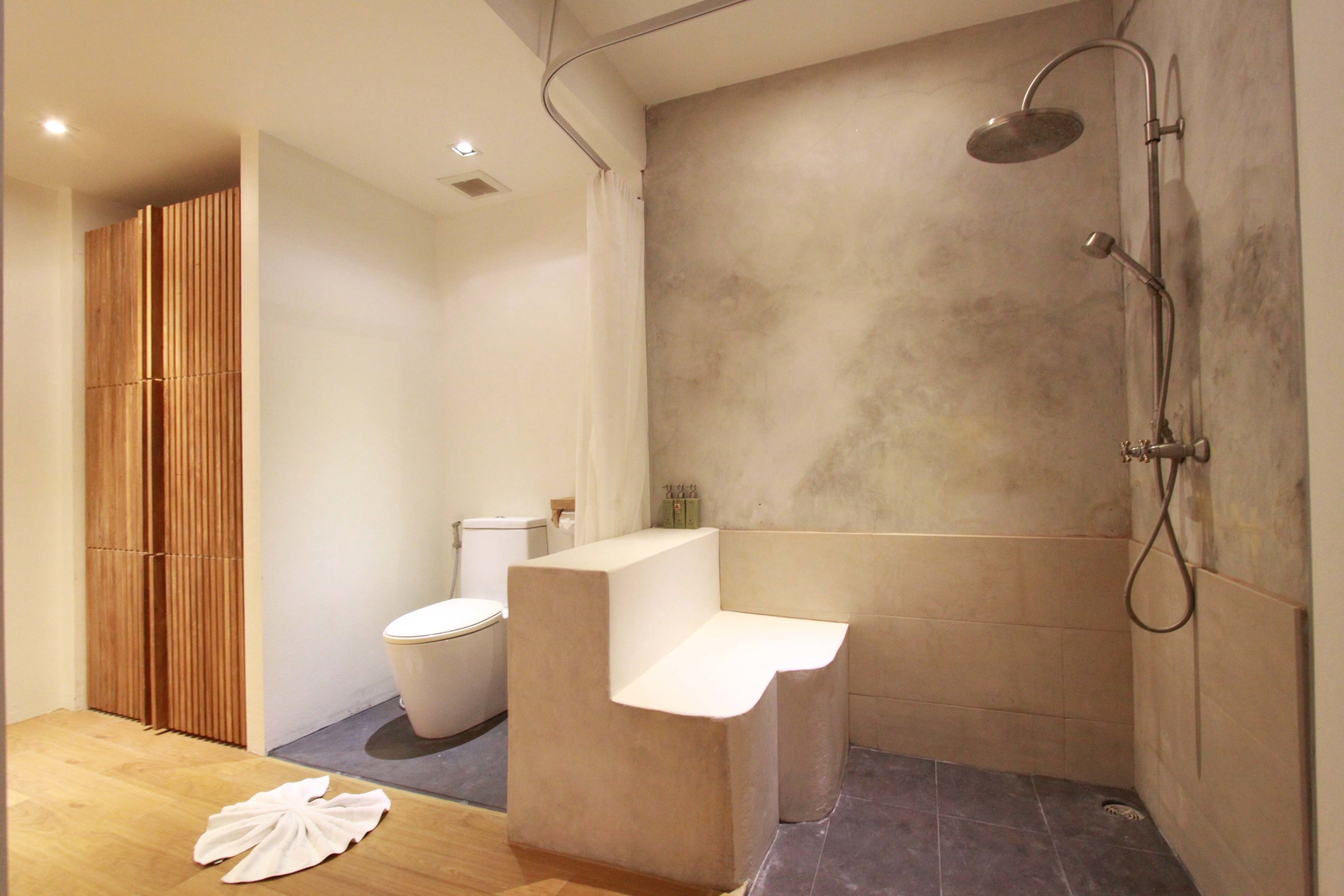 A modern bathroom with a shower, toilet, and wooden partition.
