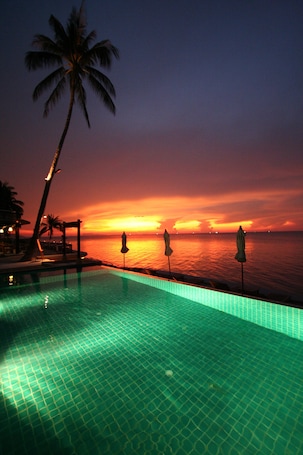 Una piscina al aire libre, sombrillas, sillones reclinables de piscina