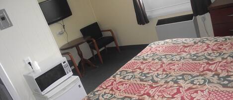 Une chambre d’hôtel équipée d’un lit, d’un bureau, d’une chaise, d’une télévision et d’un four à micro-ondes.