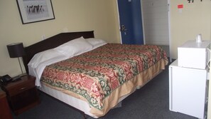 A hotel room with a bed, a nightstand, a lamp, a microwave, and a notice on the wall. - Empress Inn and Suites by The Falls (Niagara Falls)