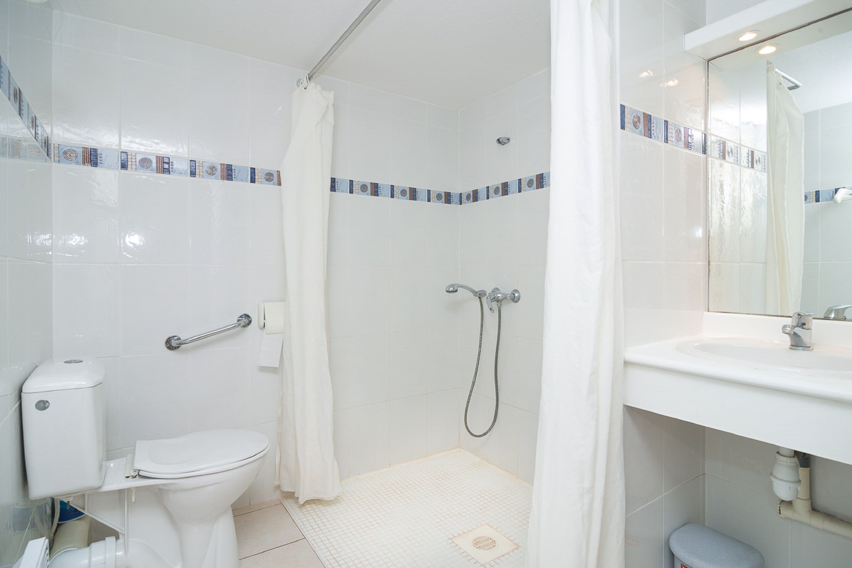 A bathroom with a toilet, shower, and sink.