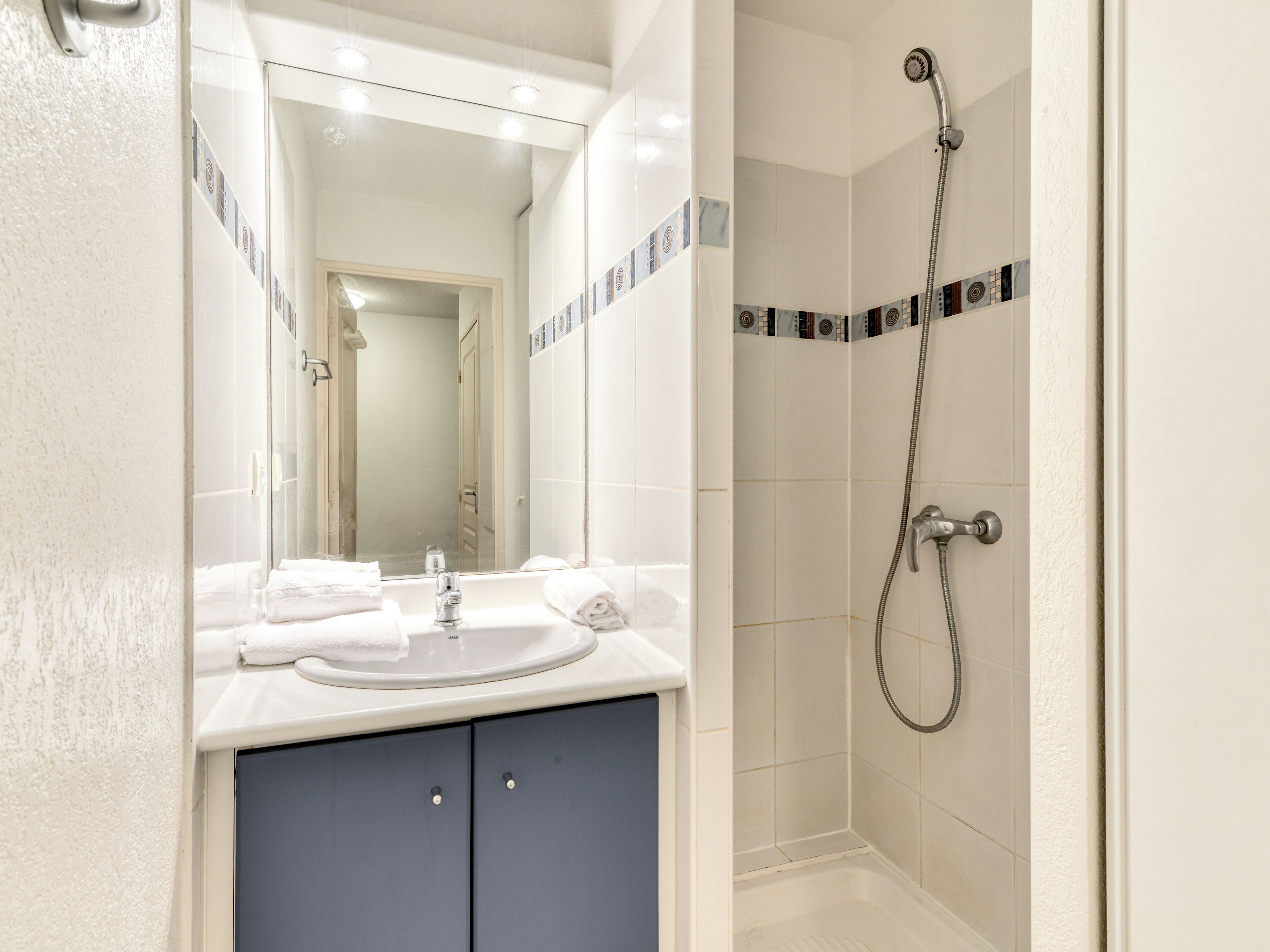 A modern bathroom with a sink, mirror, and shower.