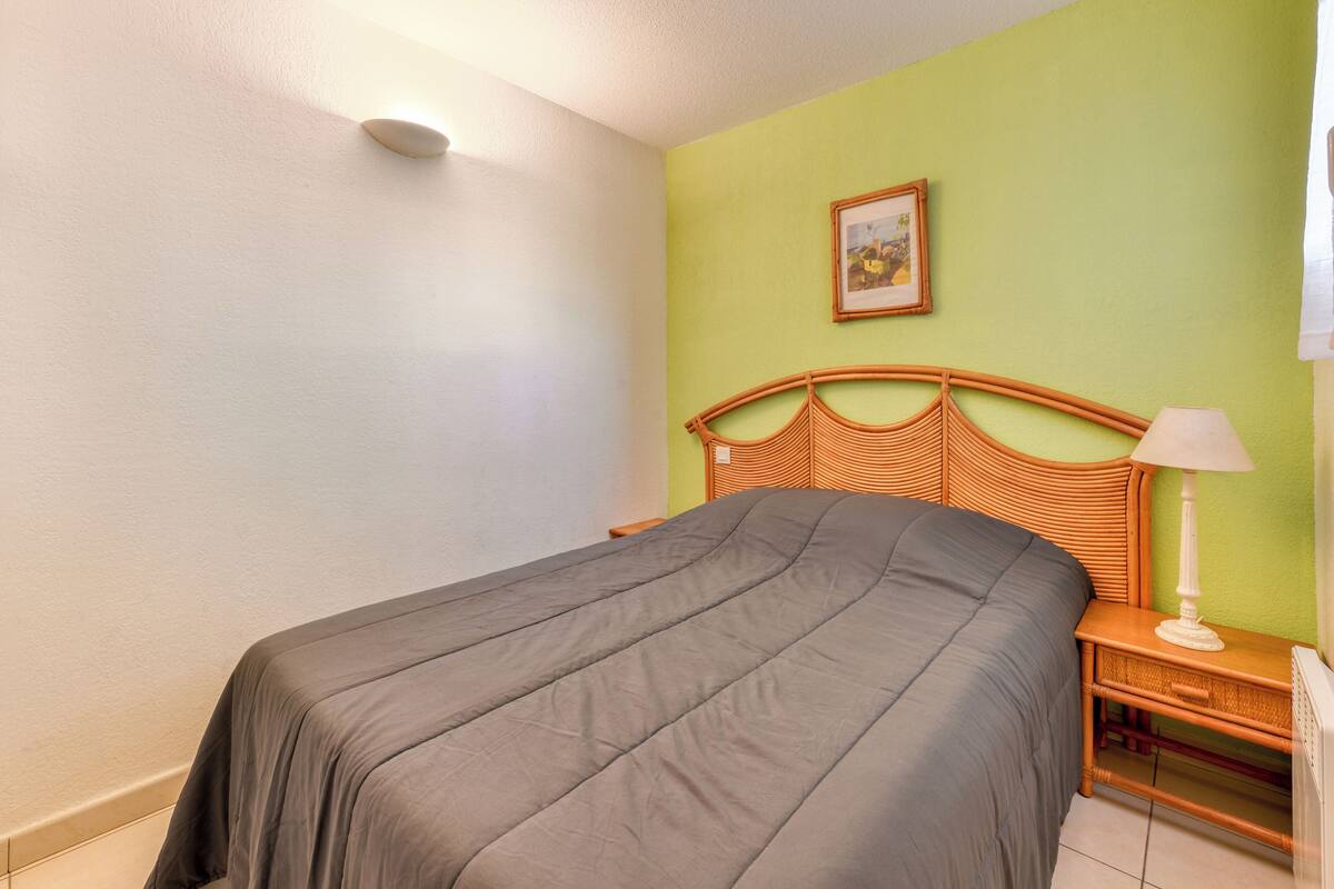 Ein Schlafzimmer mit Bett, Nachttisch, Lampe und einem Bild an der Wand.
