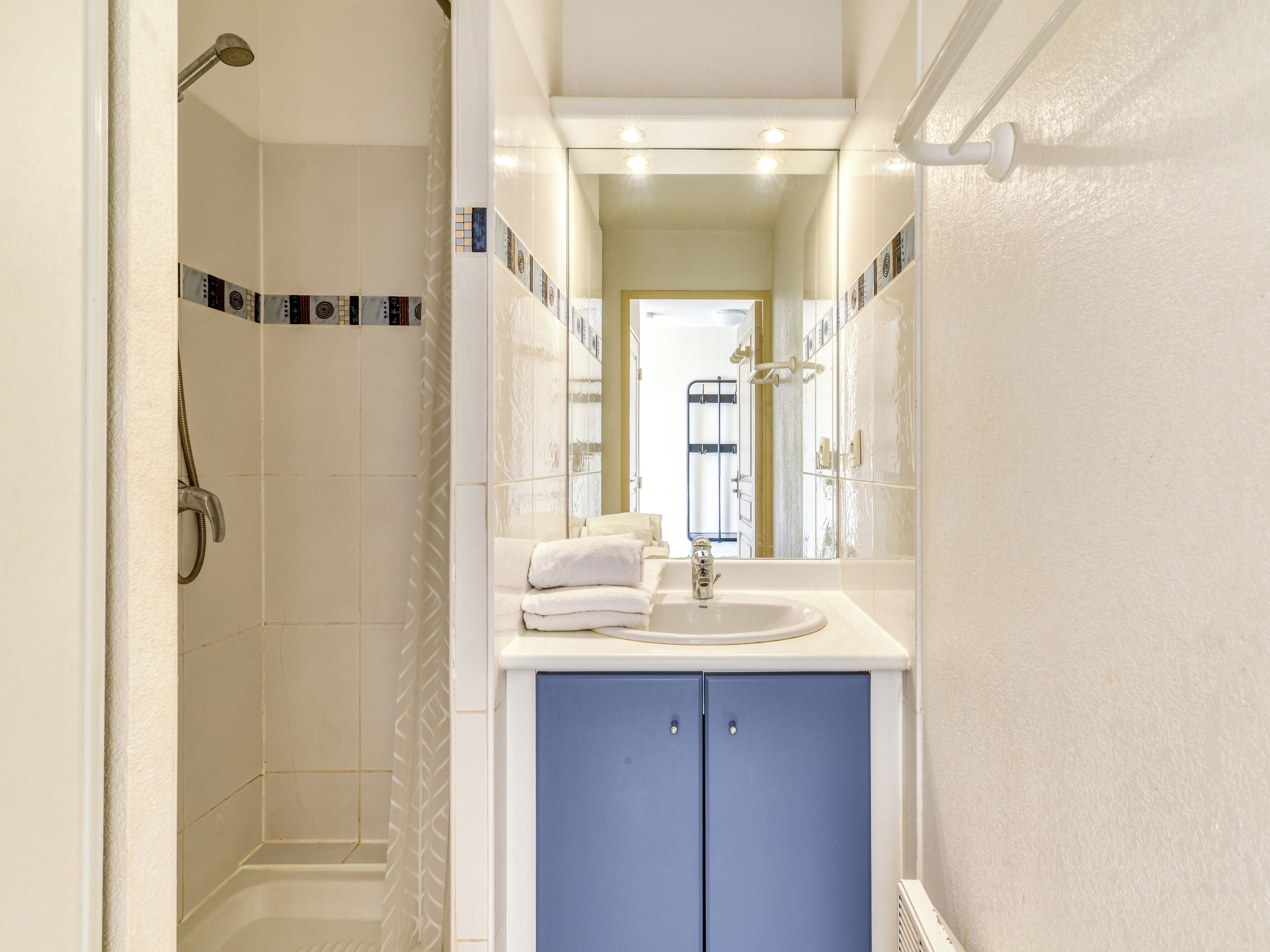 A bathroom with a shower, a sink, and a mirror.