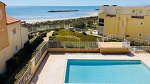 Zona de piscina con vista despejada al mar y una playa al fondo.