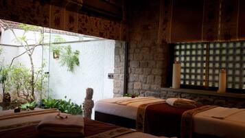 Relax in this serene spa room with two beds, a rose, and a potted plant, surrounded by a rustic charm.