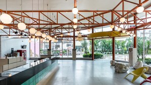 A spacious lobby with a reception desk, large windows, and a view of the outdoors. - Bella Express (Pattaya)