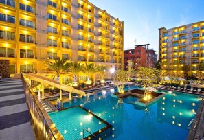 Un hotel con varios balcones, piscina y palmeras.