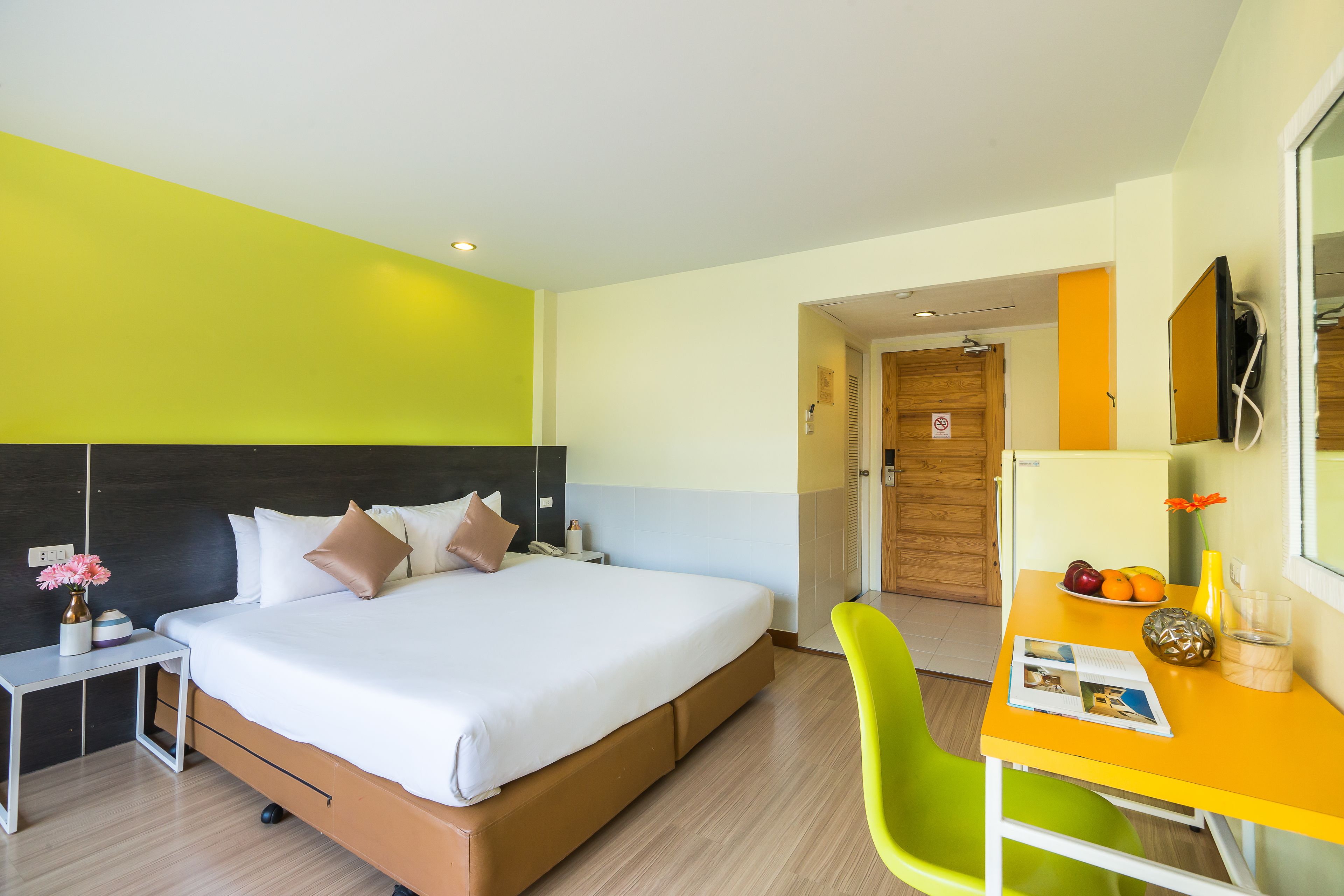 A hotel room with a bed, a desk, a chair, and a dining table.
