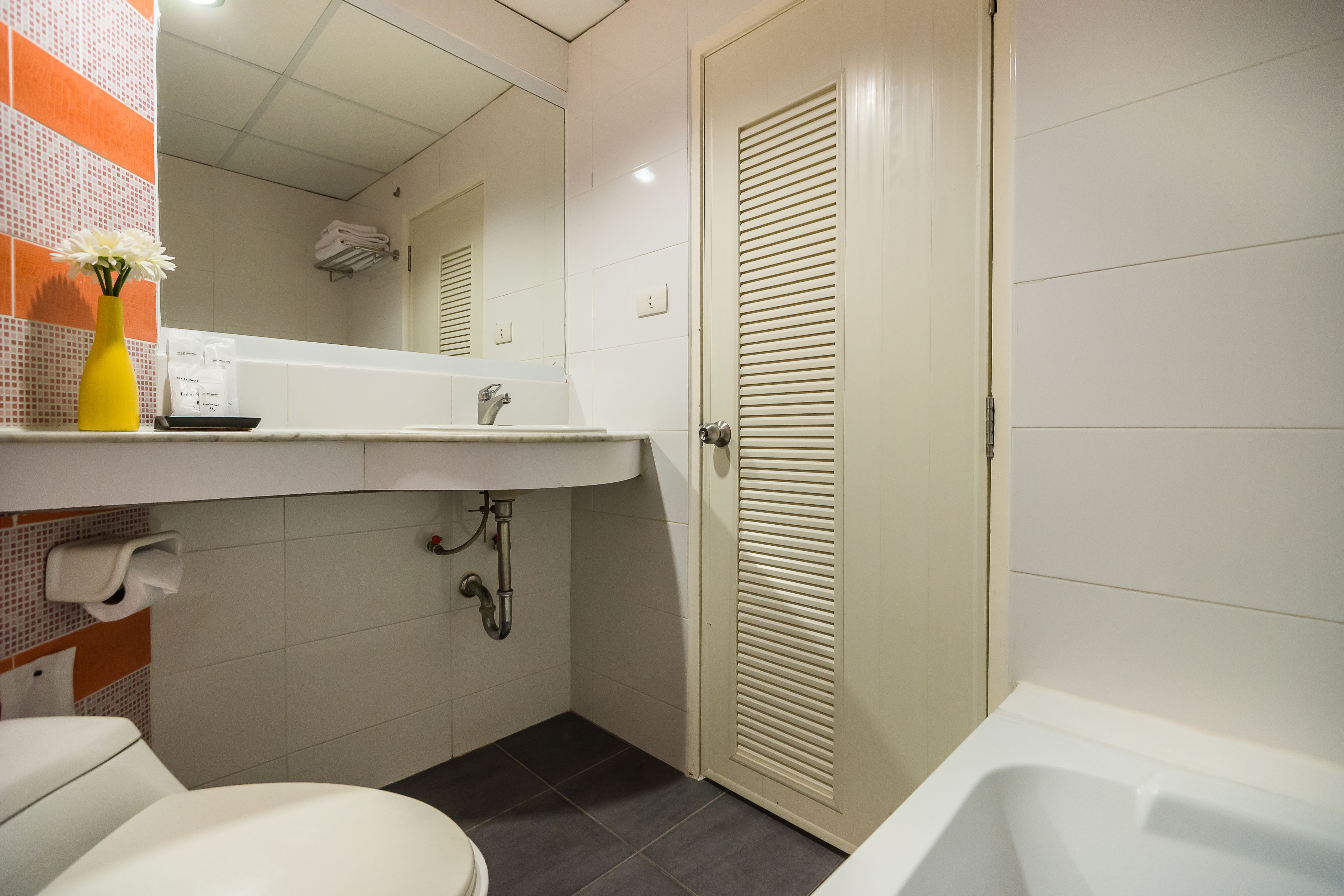 Een kleine badkamer met toilet, wastafel en bad.