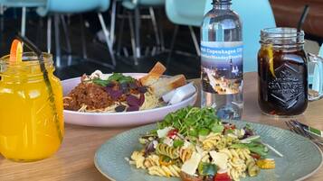 A table with two plates of food, a bottle of water, and a jar of sauce.