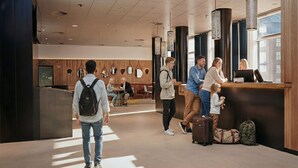 Eine moderne Hotelhalle mit einer Rezeption, einer Sitzecke und großen Fenstern.