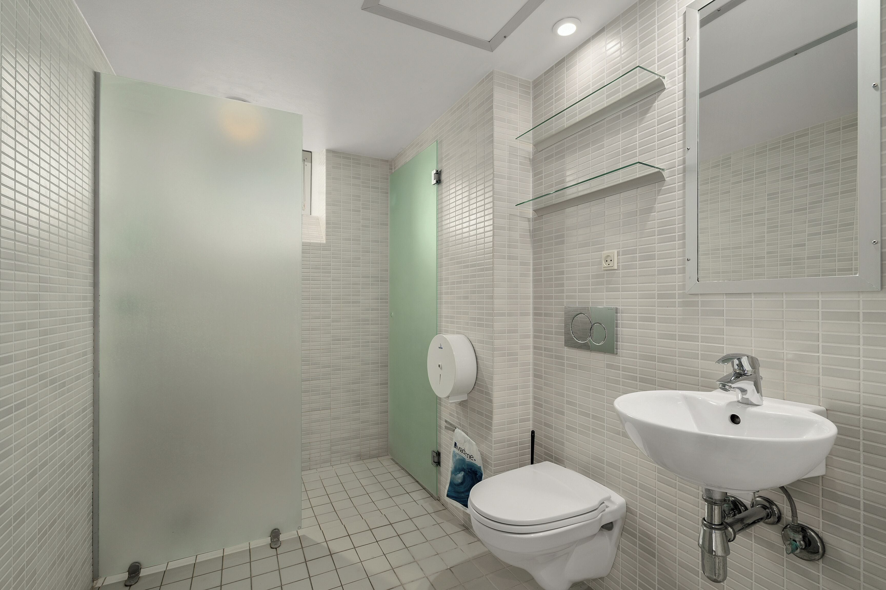 Un baño moderno con inodoro, lavamanos y cabina de ducha de vidrio.