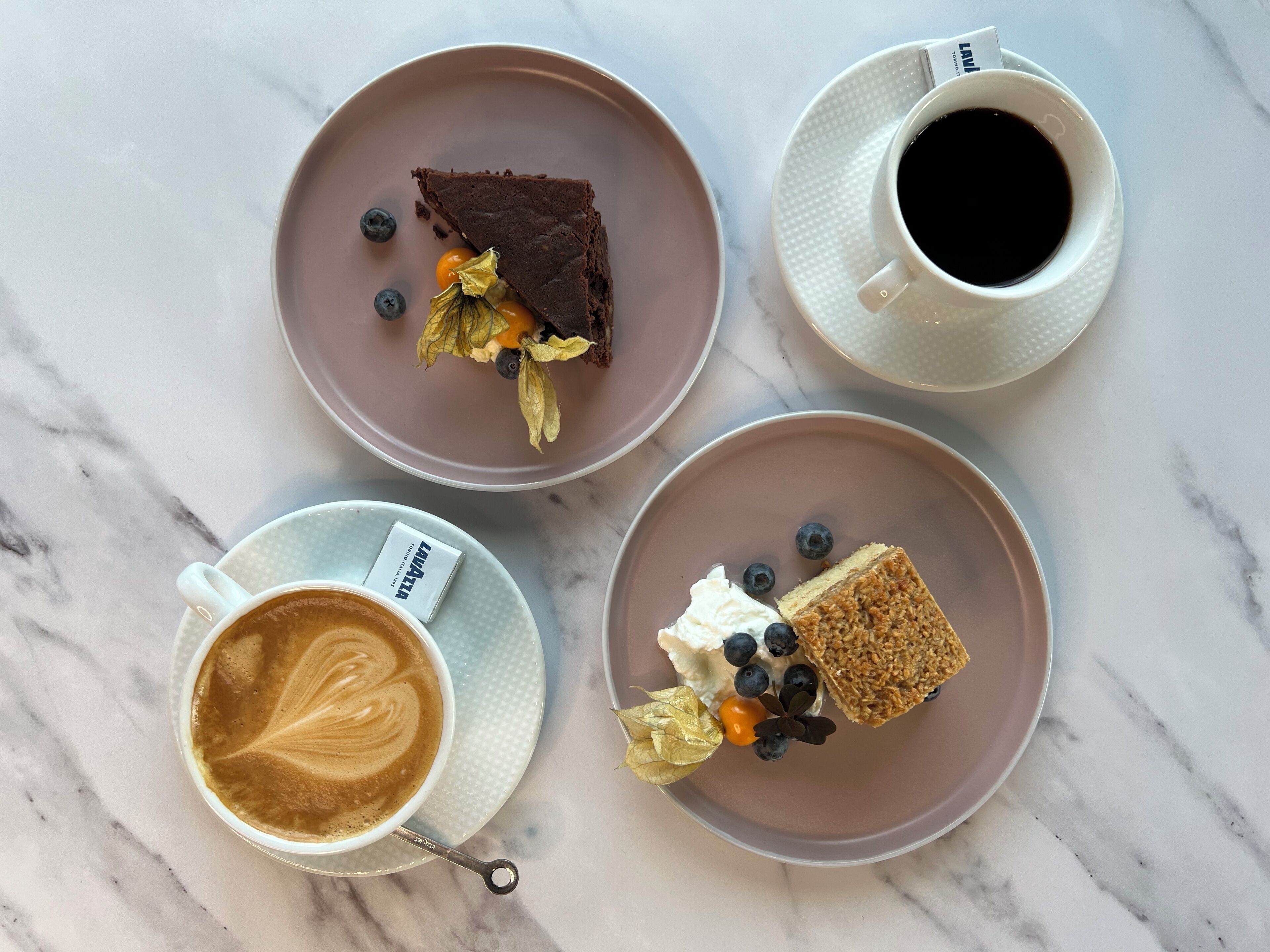 A top-down view of a table with four plates of food and three cups of beverages.