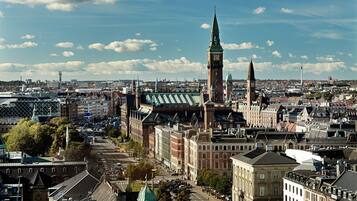 Een historisch stadsgezicht met opvallende gebouwen, waaronder een klokkentoren en een kerk met een groen dak.