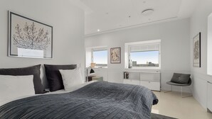Ein modernes Schlafzimmer mit einem großen Bett, einem Schreibtisch und einem Stuhl, alles im minimalistischen Stil.