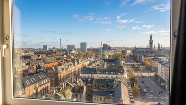 Eine Stadtansicht mit historischen Gebäuden, einem markanten Turm und einer großen, grünen Kuppel.