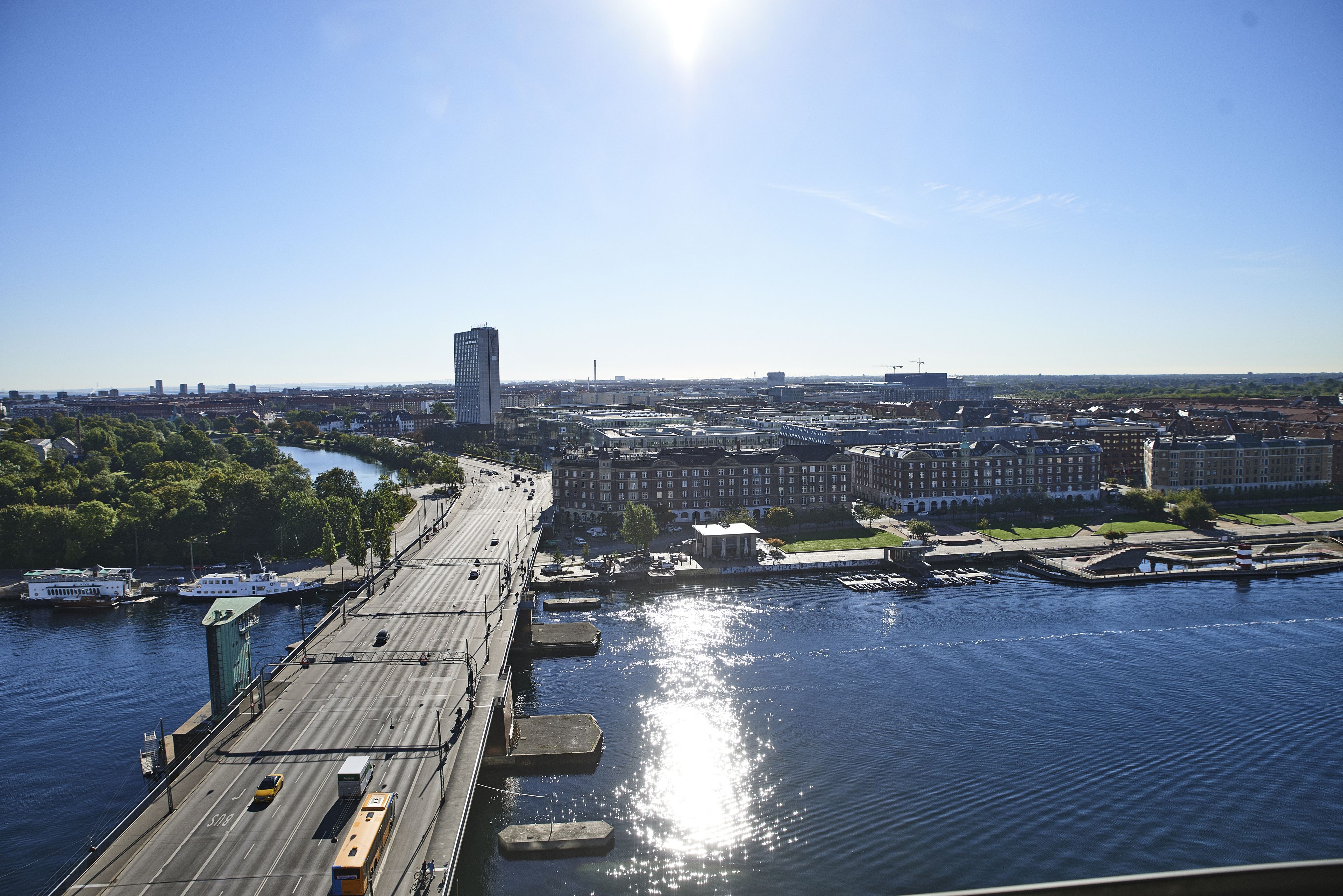 A riverfront bridge with a view of the cityscape, including buildings and a tall skyscraper.