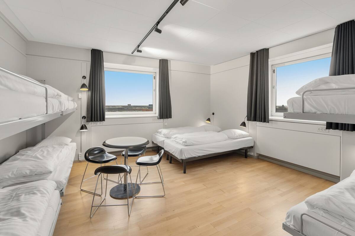 Une chambre d’hôtel moderne avec des lits superposés, une table à manger ronde et deux chaises.