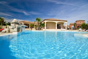 Una piscina azul cristalina con sillas de descanso y una estructura de piedra.