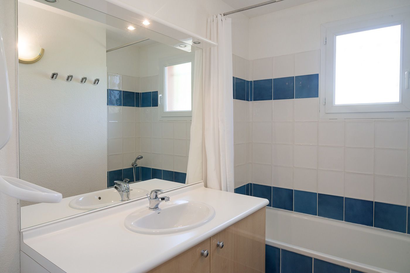 Une salle de bain avec un lavabo blanc, un miroir et un espace douche.