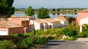 A residential area with terracotta-roofed houses, a lake, and lush greenery.
