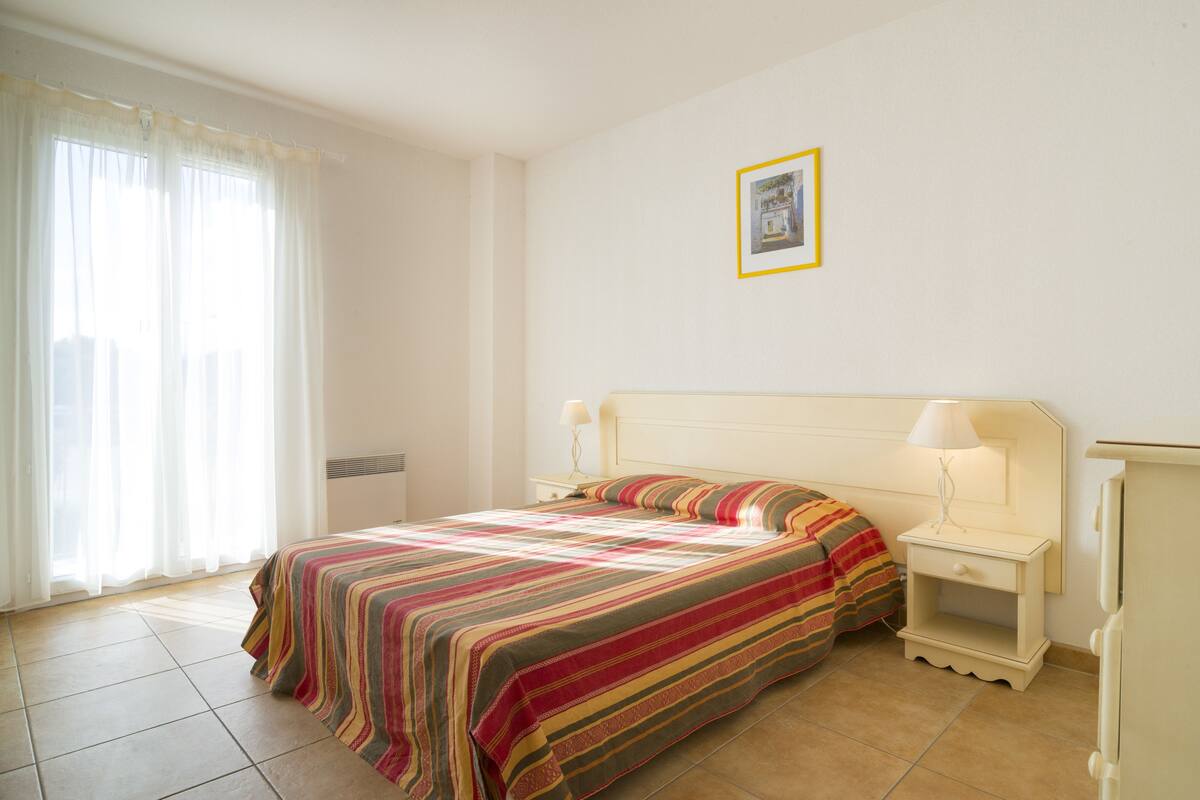 Une chambre d’hôtel avec un lit, des tables de chevet, une lampe et un tableau encadré au mur.