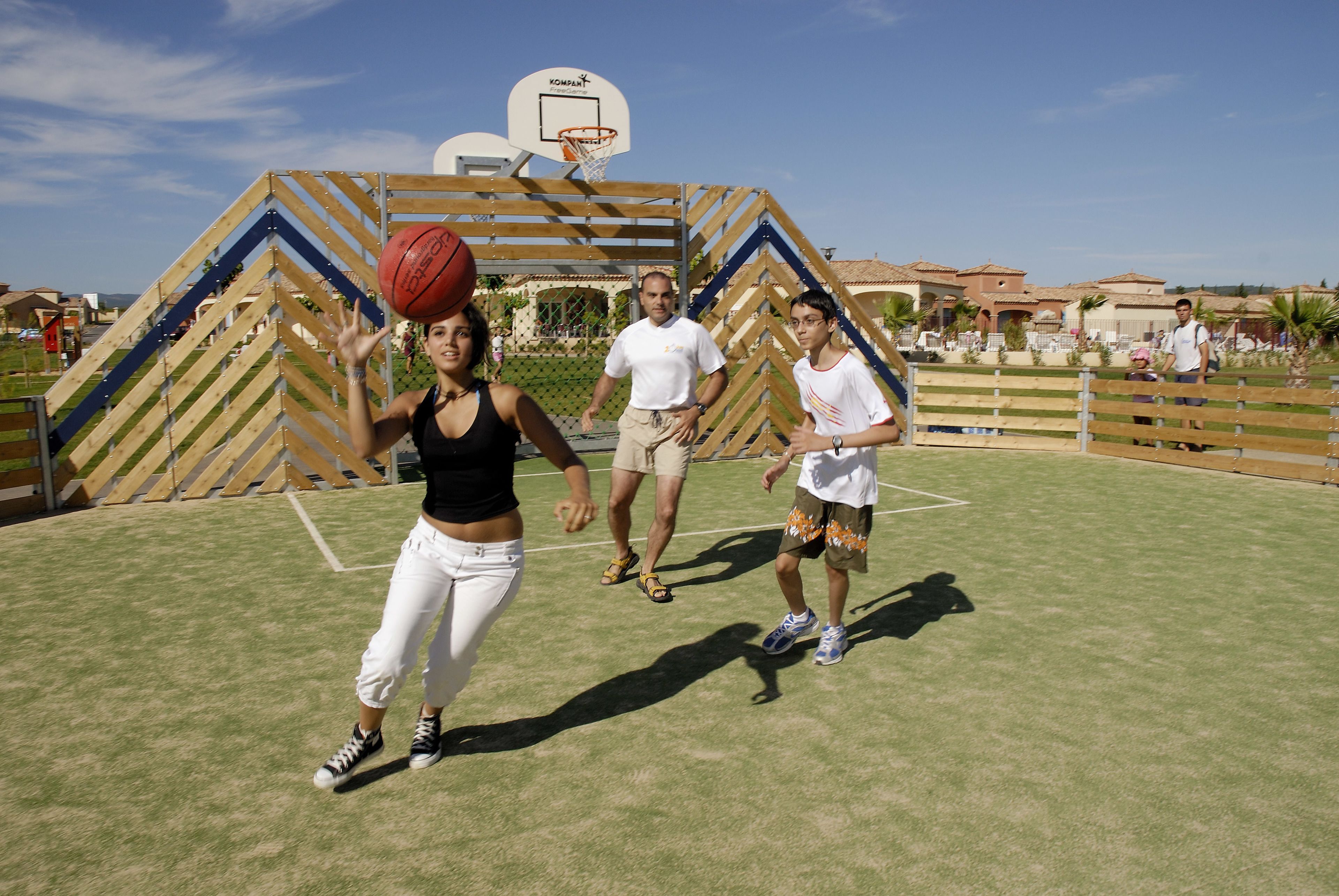 An outdoor basketball court with a wooden structure and a basketball hoop.