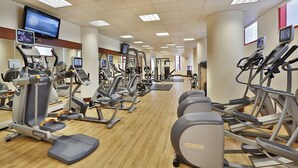 Un gimnasio con varias máquinas de cardio, incluyendo cintas de correr y elípticas, dispuestas en filas.