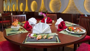 Un comedor con mesas redondas, vajilla roja y blanca, y una pared de ladrillo con aberturas circulares.