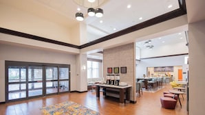 A spacious lobby with a patterned carpet, a reception desk, and a seating area with chairs and tables. - Hampton Inn & Suites Seattle/Kent,WA (Kent)