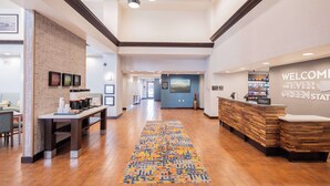 A hotel reception area with a wooden reception desk, a coffee station, and a wall-mounted TV. - Hampton Inn & Suites Seattle/Kent,WA (Kent)