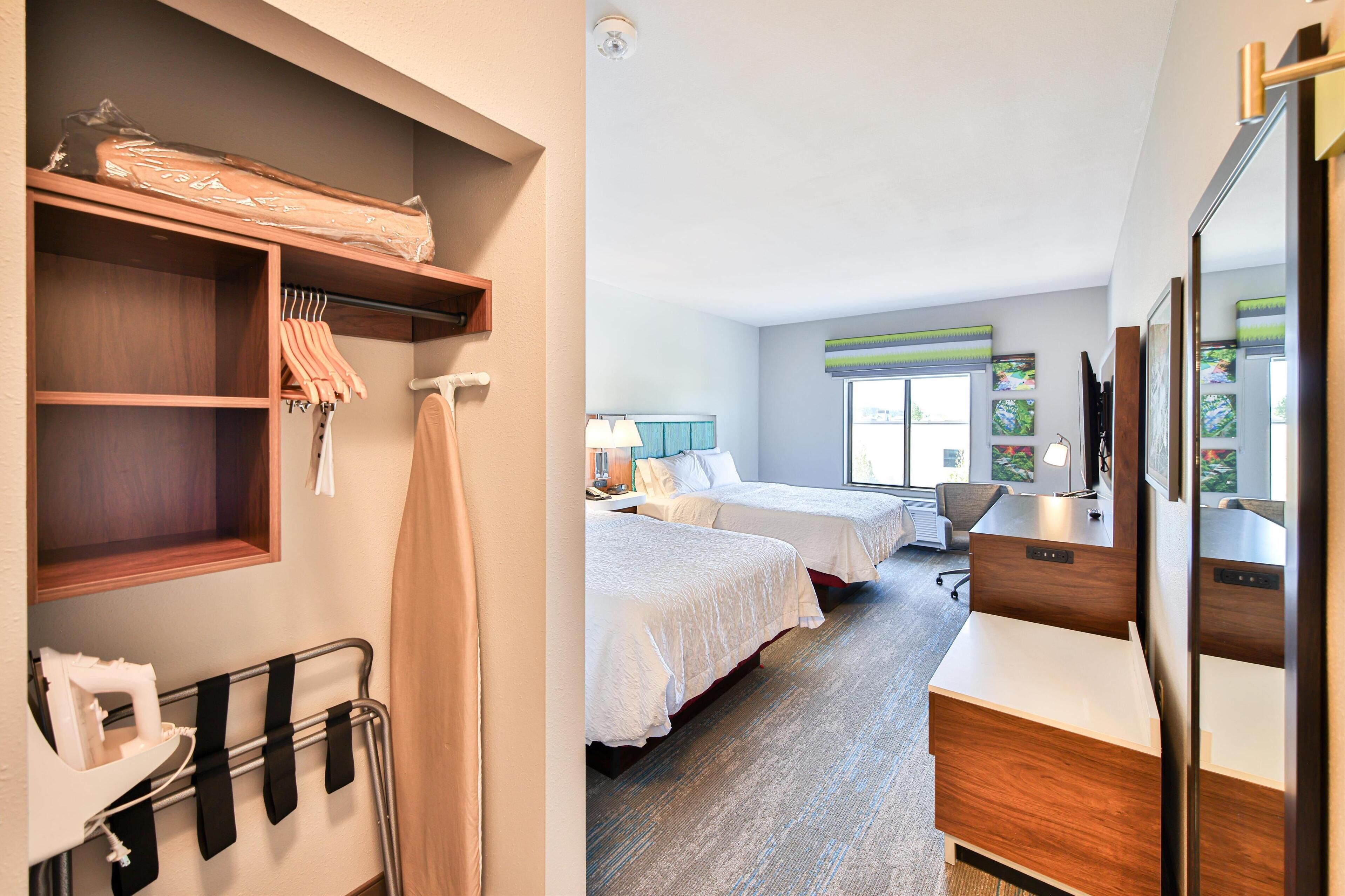 Een hotelkamer met twee bedden, een bureau en een kledingkast.