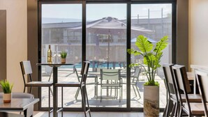 A modern indoor dining area with a view of an outdoor pool and umbrellas. - Aiden by Best Western South Reno (Reno)