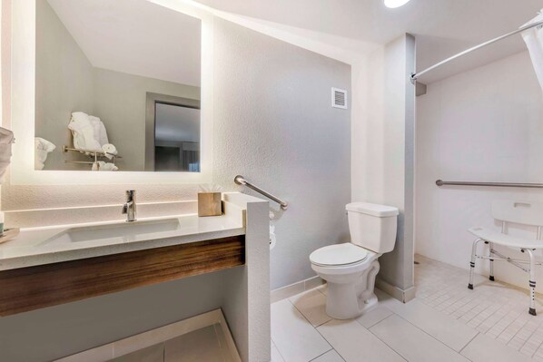 A modern bathroom with a white sink, toilet, and shower area.