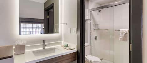 Un baño moderno con un espejo grande, un lavabo y una ducha con mampara de vidrio.