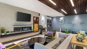 A modern lobby with a fireplace, seating area, and a wall-mounted TV. - Aiden by Best Western South Reno (Reno)