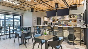 A modern cafe with a bar area, seating arrangements, and a kitchen in the background. - Aiden by Best Western South Reno (Reno)