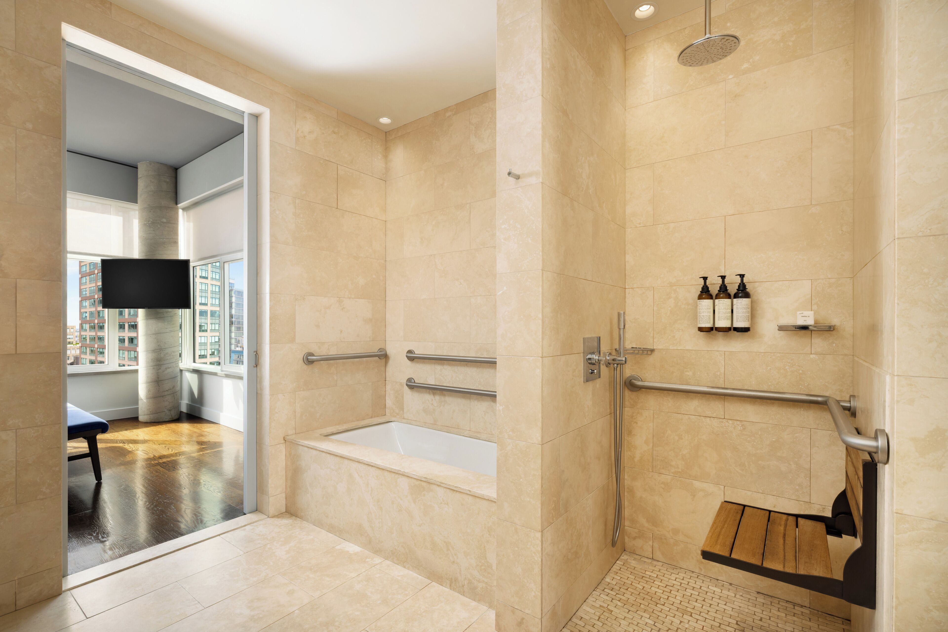 A modern bathroom with a bathtub, shower, and handrails.