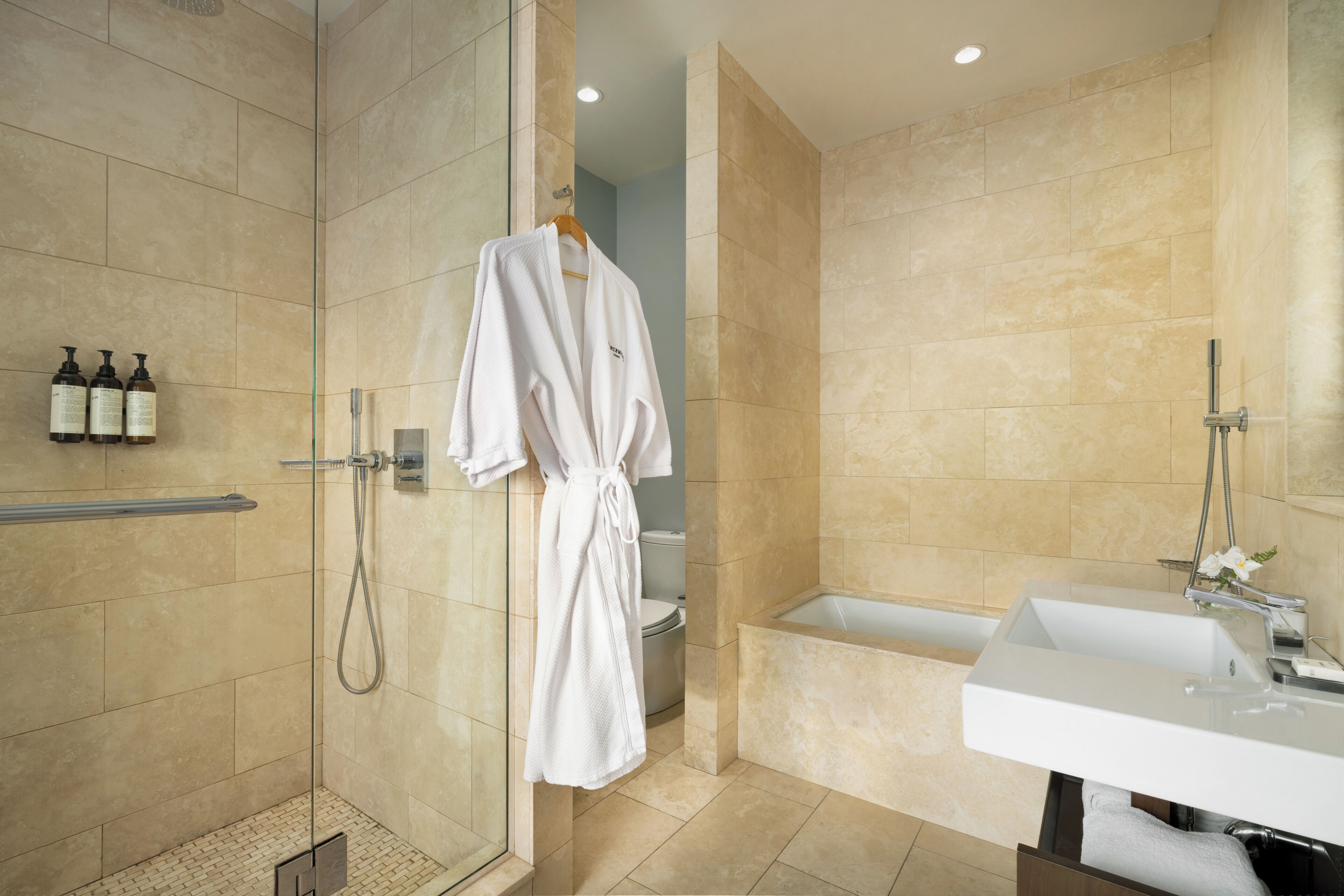 Un bagno moderno con doccia a filo pavimento, vasca e mobile lavabo.
