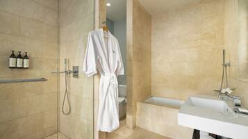 Un bagno moderno con doccia a filo pavimento, vasca e mobile lavabo.