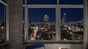 Una habitación moderna con un amplio ventanal con vistas a un paisaje urbano nocturno.